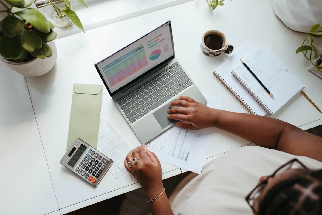 Woman business owner calculating finances at desk with laptop