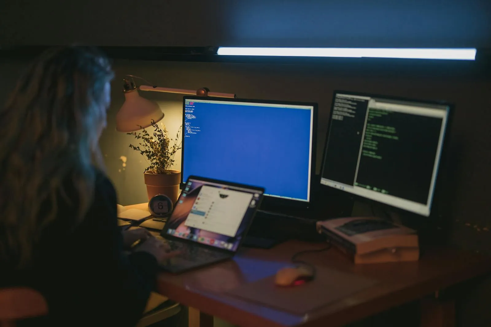 Woman using multiple screens for cybersecurity tasks in a home office