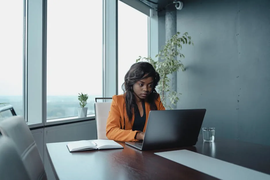 Focused businesswoman working alone at her desk with laptop and paperwork